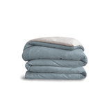 Down for Good Essential duvet cover panels, folded and stacked, in Blue Haze and Shell organic cotton.