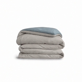 Down for Good Essential duvet cover panels, folded and stacked, in Fog and Blue Haze organic cotton.