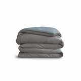 Down for Good Essential duvet cover panels, folded and stacked, in Riverbed and Blue Haze organic cotton.