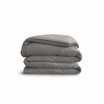 Down for Good Essential duvet cover panels, folded and stacked, in Riverbed and Fog organic cotton.