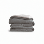 Down for Good Essential duvet cover panels, folded and stacked, in Riverbed and Shell organic cotton.
