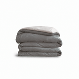 Down for Good Essential duvet cover panels, folded and stacked, in Riverbed and Shell organic cotton.