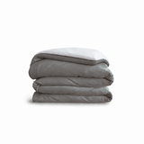 Down for Good Essential duvet cover panels, folded and stacked, in Riverbed and White organic cotton.