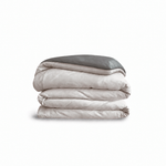 Down for Good Essential duvet cover panels, folded and stacked, in Shell and Riverbed organic cotton.