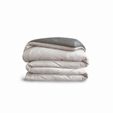 Down for Good Essential duvet cover panels, folded and stacked, in Shell and Riverbed organic cotton.
