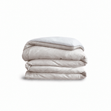 Down for Good Essential duvet cover panels, folded and stacked, in Shell and White organic cotton.