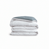 Down for Good Essential duvet cover panels, folded and stacked, in White and Blue Haze organic cotton.