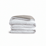 Down for Good Essential duvet cover panels, folded and stacked, in White and Fog organic cotton.