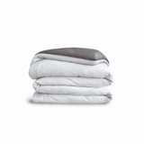 Down for Good Essential duvet cover panels, folded and stacked, in White and Riverbed organic cotton.