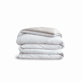 Down for Good Essential duvet cover panels, folded and stacked, in White and Shell organic cotton.